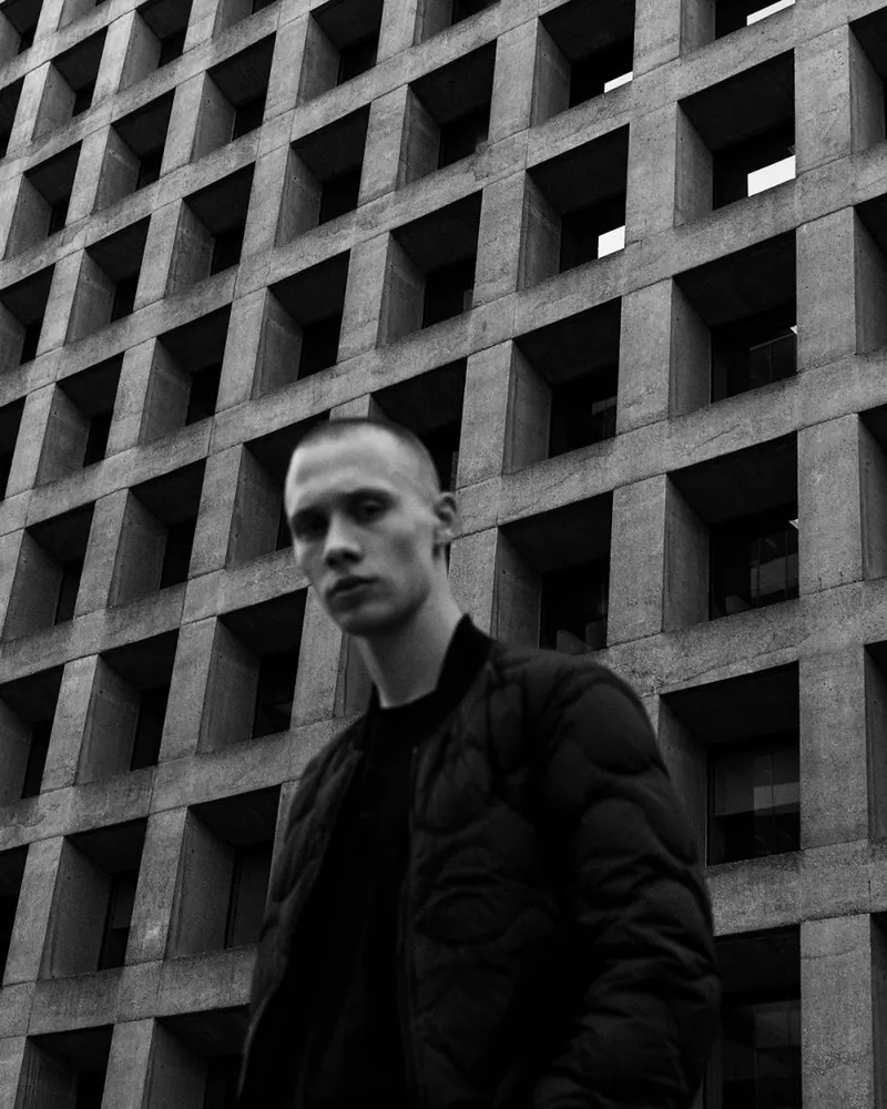 A man beside a geometric concrete wall