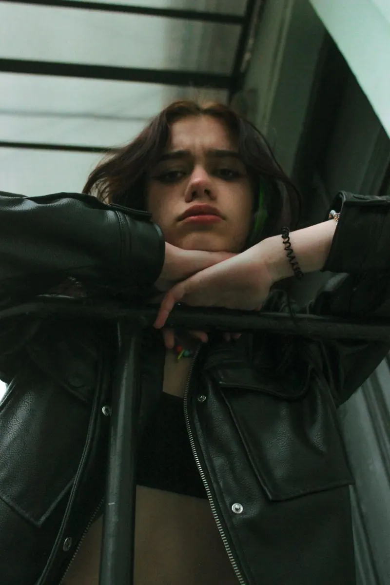 A leather jacket beside a green-lit window — men's portrait