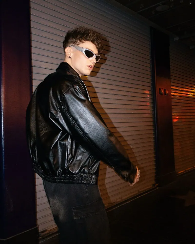 A black leather jacket on a city street at night — men's portrait