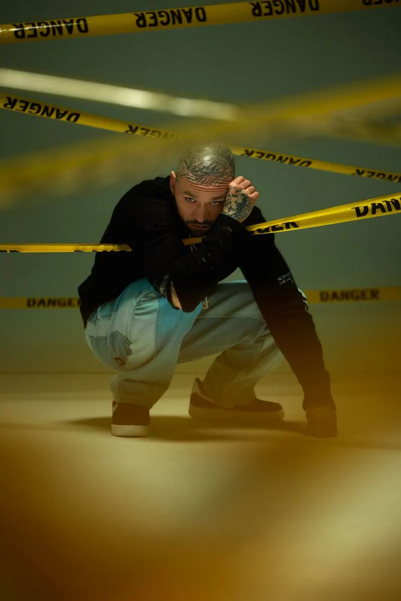 A man in black behind yellow tape on a street