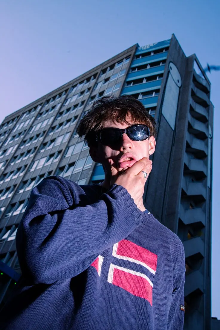 A hoodie and sunglasses below a tower block — women's portrait