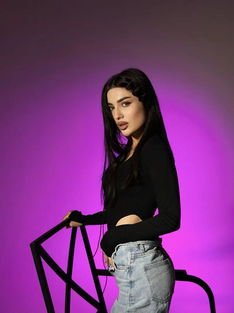 A black top by a railing in purple light — women's portrait
