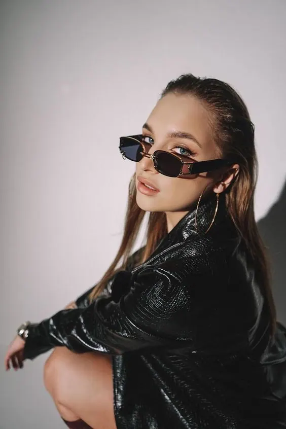 Chaqueta de cuero y gafas sobre fondo gris — retrato de mujer