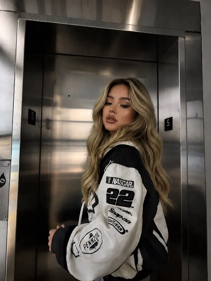 Una chaqueta universitaria en un ascensor de acero — retrato de mujer