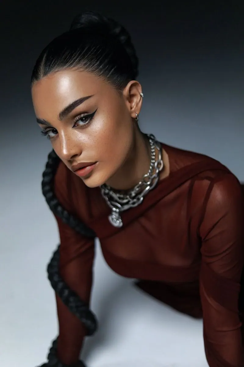 A sleek braid and chains on grey — women's portrait
