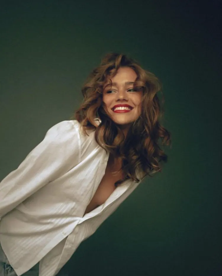 A loose white shirt against a dark green backdrop — women's portrait
