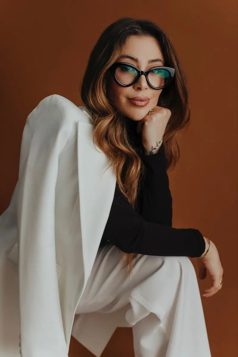 A cream suit with green-framed glasses — women's portrait