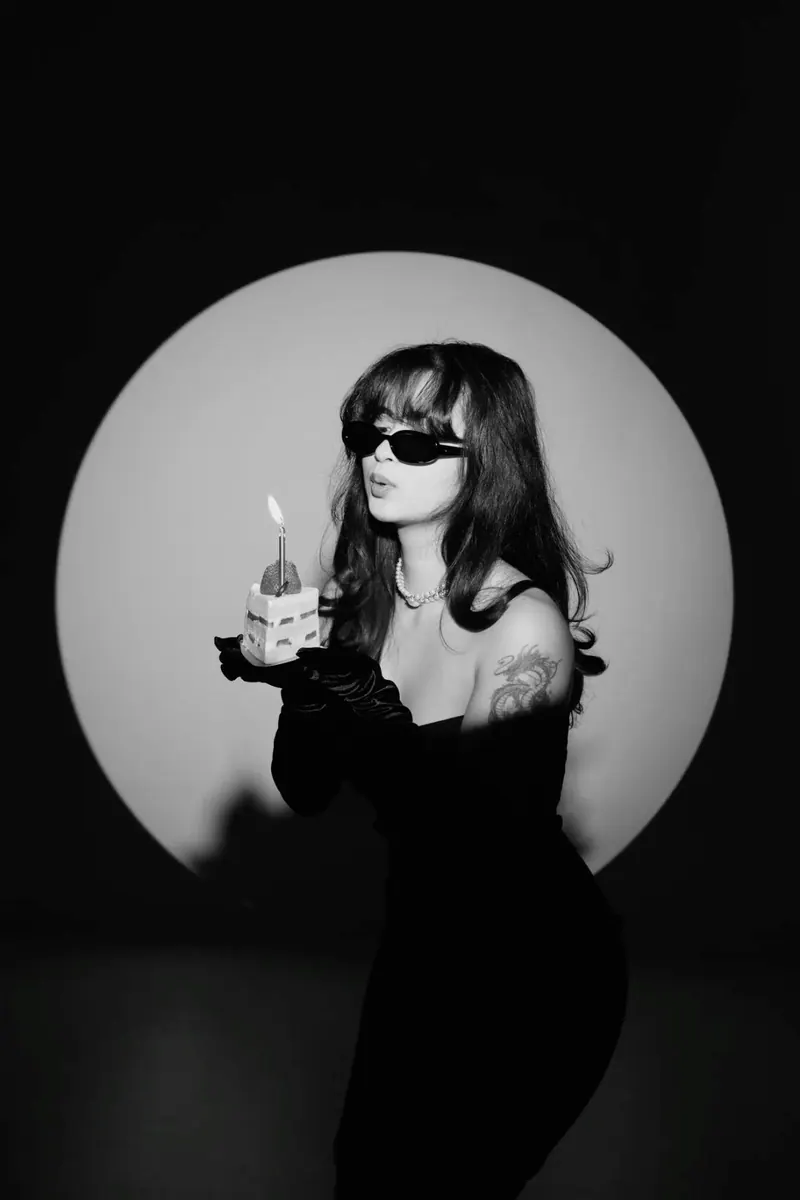 A circular spotlight behind a woman on black