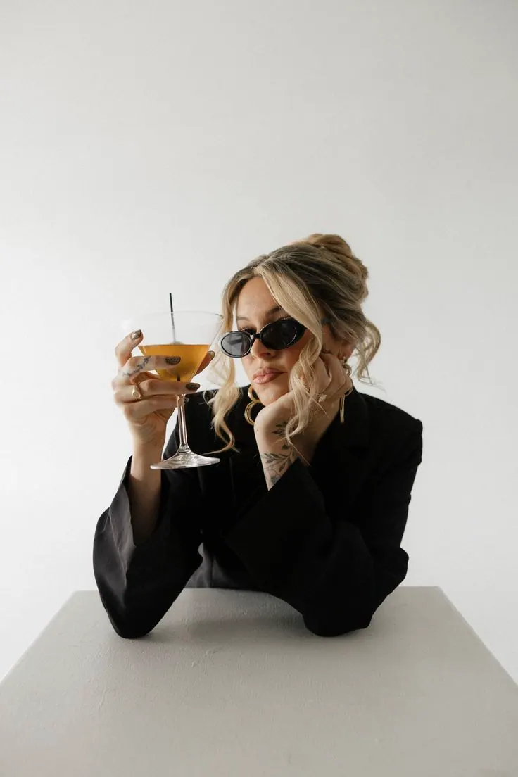 A black blazer and sunglasses at a white table — women's portrait