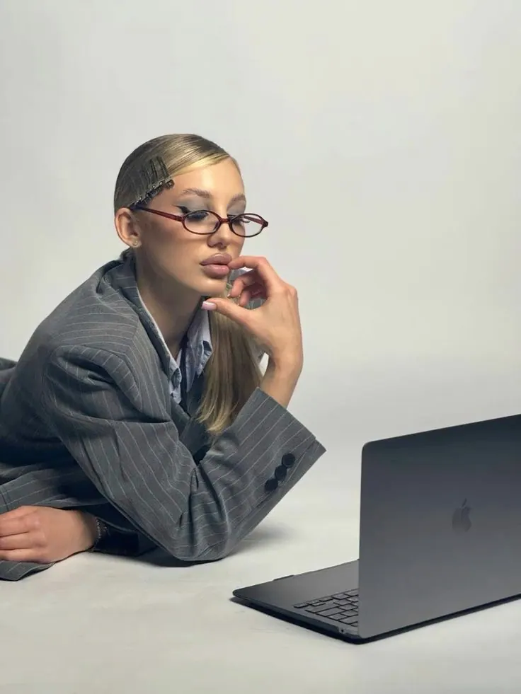 A grey blazer and laptop in a bright office portrait — women's portrait