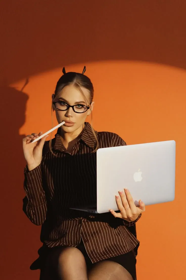 A laptop and office outfit against orange — women's portrait