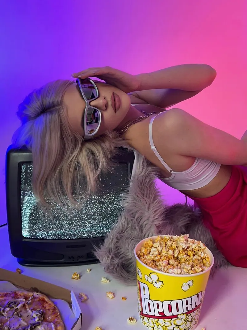 A retro television and popcorn in pink light — women's portrait