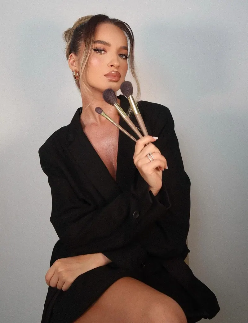 Makeup artist photoshoot — a makeup artist holding brushes in a black blazer