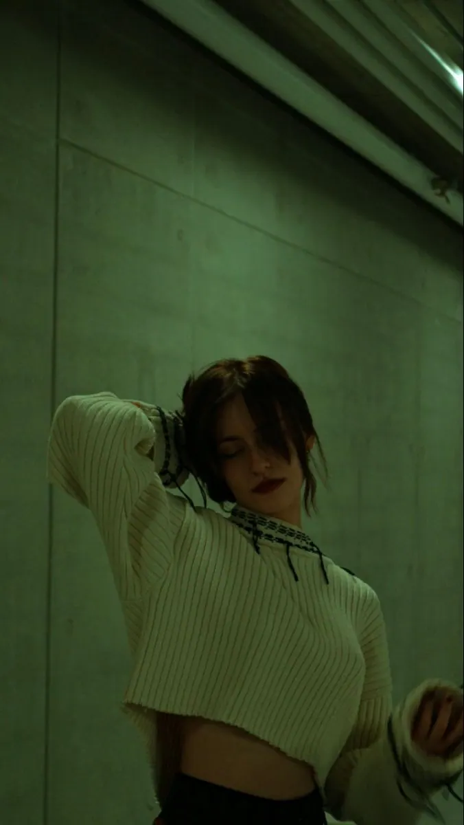 A white tee under green light in a hallway — women's portrait