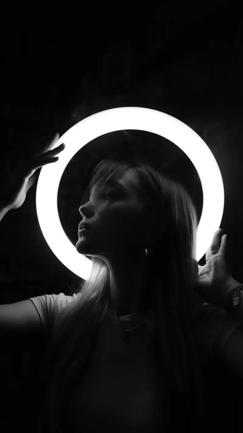 A dark silhouette in front of a circular light — women's portrait