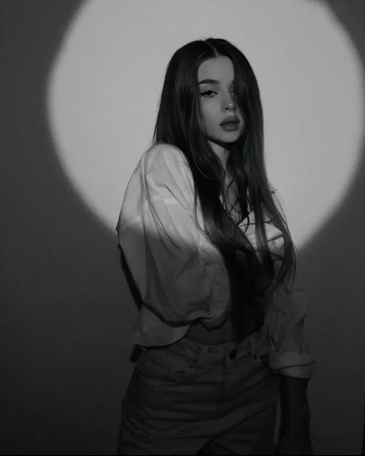 A circle of light behind a white shirt in monochrome — women's portrait
