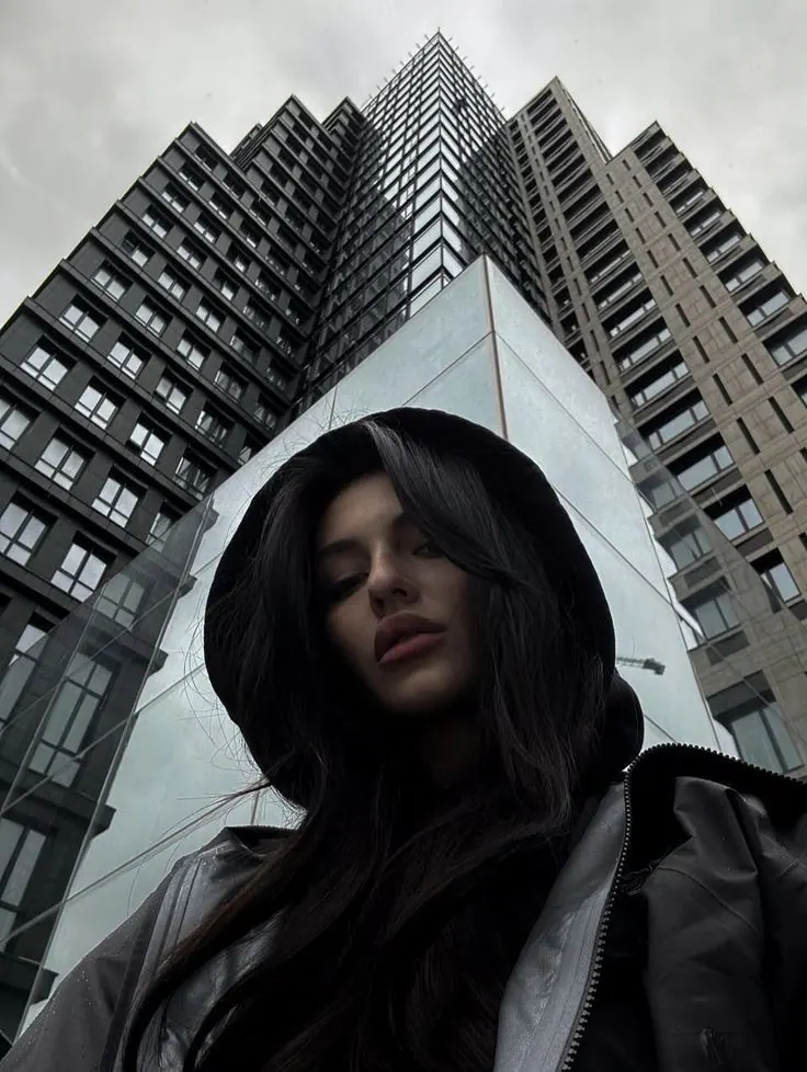 A hood beneath tall city towers — women's portrait