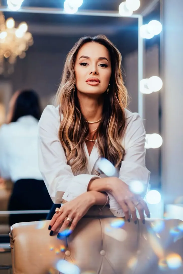 A woman beside a lit makeup mirror